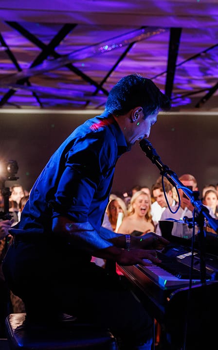 piano player singing into microphone and playing piano on stage