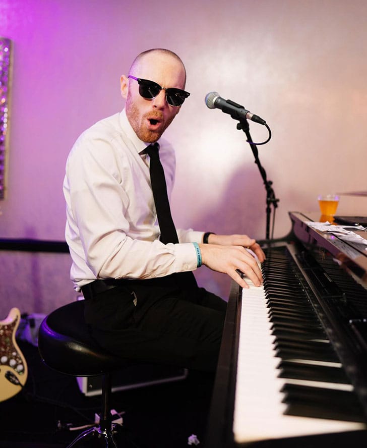 greg wearing glasses playing the piano