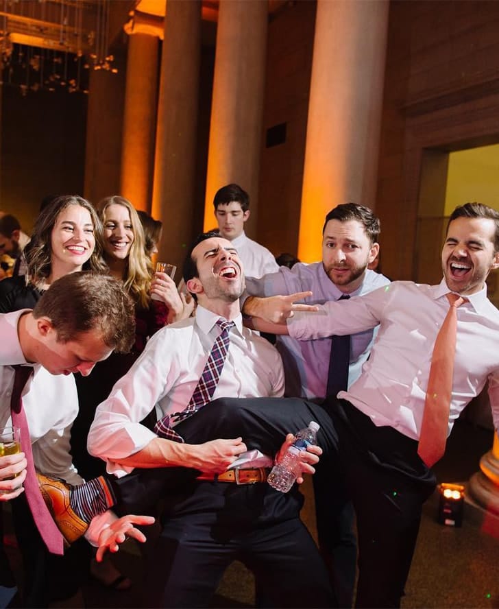 group of guests dancing at wedding using leg as guitar