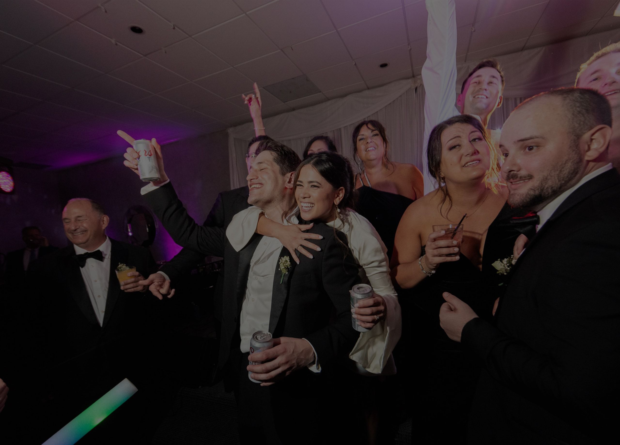 group of guests singing and dancing at wedding with dark overlay
