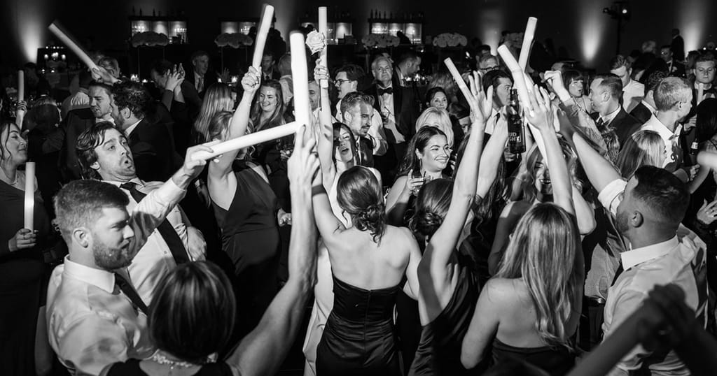 black and white portrait of bride and groom and guests dancing on dance floor