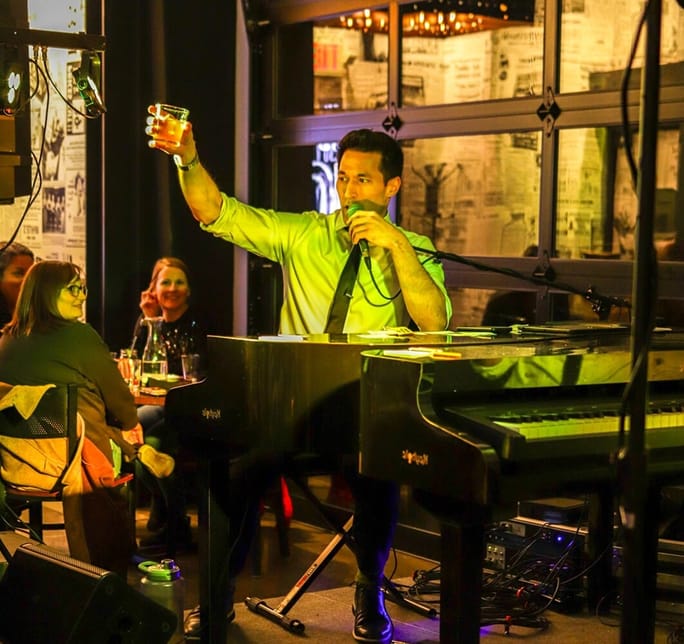 piano player holding drink up toasting